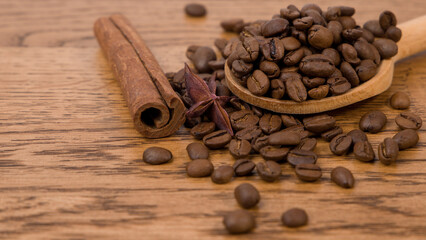 Coffee beans and cinnamon sticks on a wooden background, close up