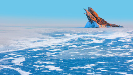 Beautiful winter landscape of frozen Lake Baikal at sunrise - A granite rock with steep slopes...
