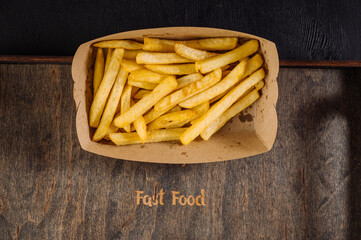 Tasty fast food, fried french fries takeaway in paper box on background