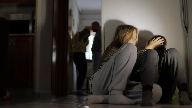 domestic violence, in the foreground the daughter and son are sitting on the floor