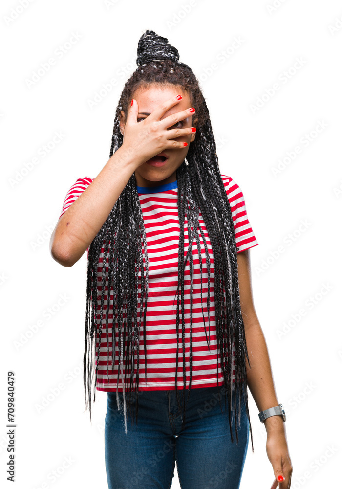 Sticker Young braided hair african american girl over isolated background peeking in shock covering face and eyes with hand, looking through fingers with embarrassed expression.