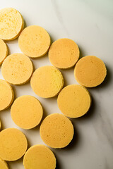 Freshly baked halves of beige macaroons lie on a table