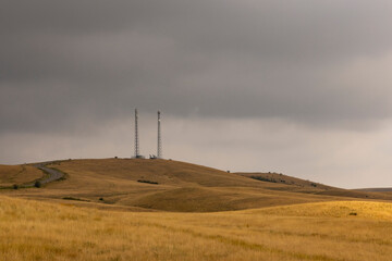 Communication tower in field with dark storm clouds