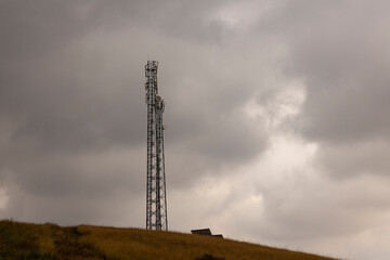 Communication tower in field with dark storm clouds