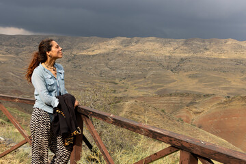portrait of woman smiling at kakheti steppe landscape with dry neadow and sandstone mountains in...