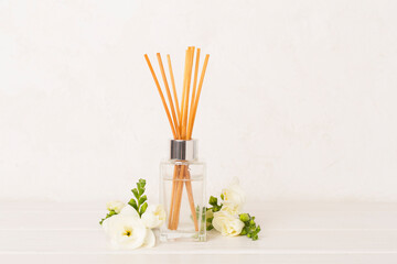 Reed aroma diffuser with freesia flower on wooden table