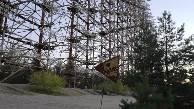 Zoom out from abandoned radiation sign with Duga horizon radar systems on background in Chernobyl, Ukraine 