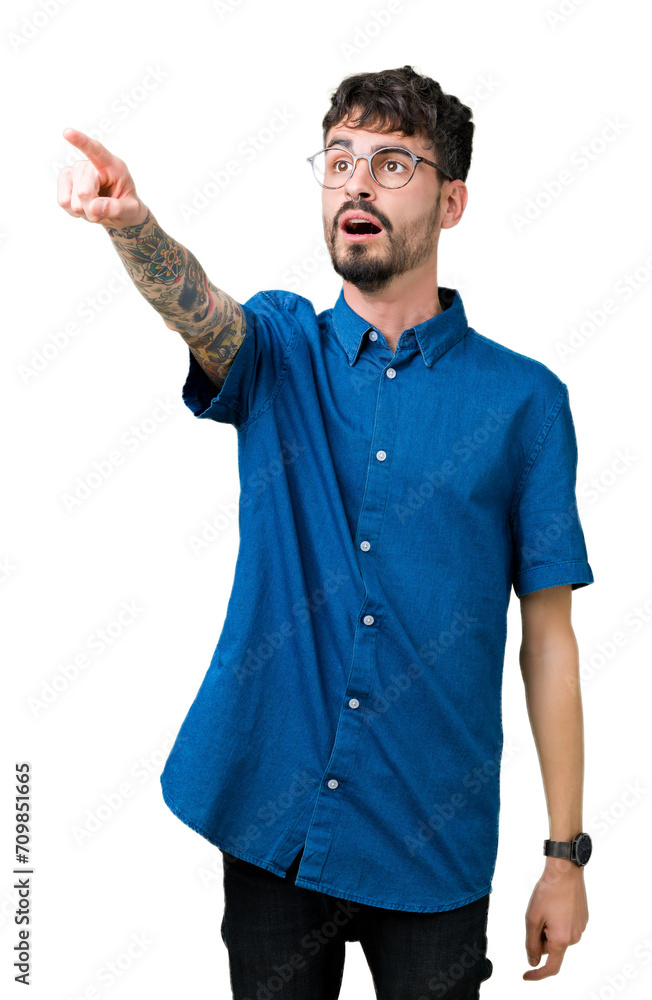 Poster Young handsome man wearing glasses over isolated background Pointing with finger surprised ahead, open mouth amazed expression, something in front