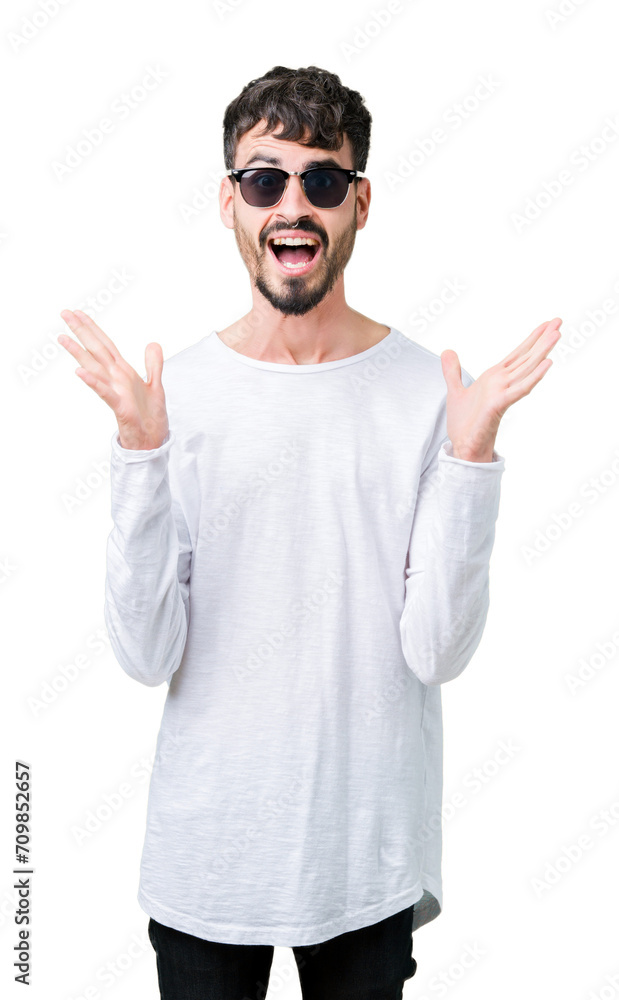 Sticker Young handsome man wearing sunglasses over isolated background celebrating crazy and amazed for success with arms raised and open eyes screaming excited. Winner concept