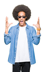 Young african american man with afro hair wearing thug life glasses celebrating mad and crazy for...