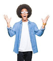 Young african american man with afro hair wearing thug life glasses celebrating crazy and amazed...