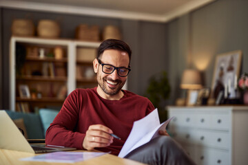 A cheerful remote accountant with glasses reading male financial reports while working from home.