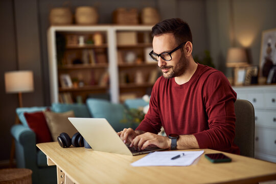 A focused male content creator typing on his laptop while working from home.