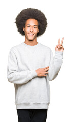 Young african american man with afro hair wearing sporty sweatshirt smiling with happy face winking at the camera doing victory sign. Number two.