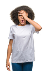 Young afro american woman over isolated background peeking in shock covering face and eyes with hand, looking through fingers with embarrassed expression.