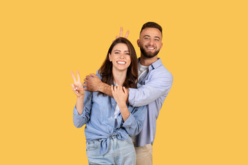 Playful couple with woman showing peace sign, man behind