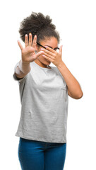 Young afro american woman wearing glasses over isolated background covering eyes with hands and doing stop gesture with sad and fear expression. Embarrassed and negative concept.