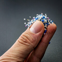 Micro plastic.Small Plastic pellets on the finger.