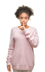 Young afro american woman wearing winter sweater over isolated background asking to be quiet with finger on lips. Silence and secret concept.