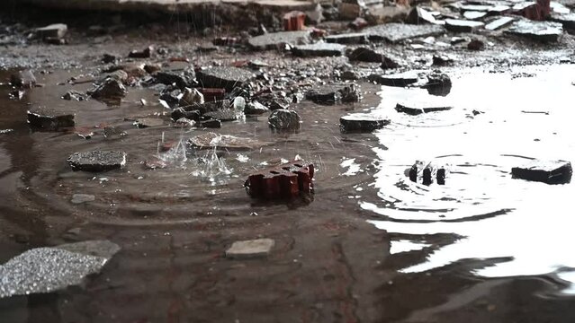 Drops of water fall into a puddle. Dripping water. Wall debris in ruined and damaged building as war aftermath in Bosnia and Herzegovina. Destroyed buildings in war by artillery. Abandoned buildings. 