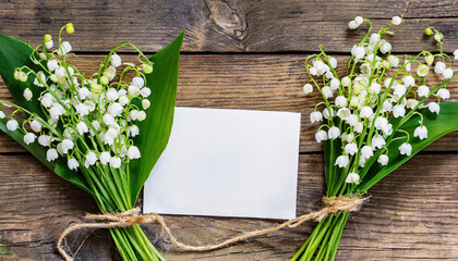 Blank greeting card with spring Lily of the valley flowers on rustic wooden background. Wedding invitation. Womens day, Valentines day card. Mock up. Flat lay