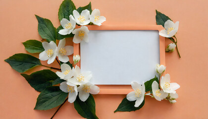 Greeting, invitation blank card in frame made of white jasmine flowers on trendy peach color background, copy space. Mock up. Flat lay. Top view. Romantic wedding holiday celebration