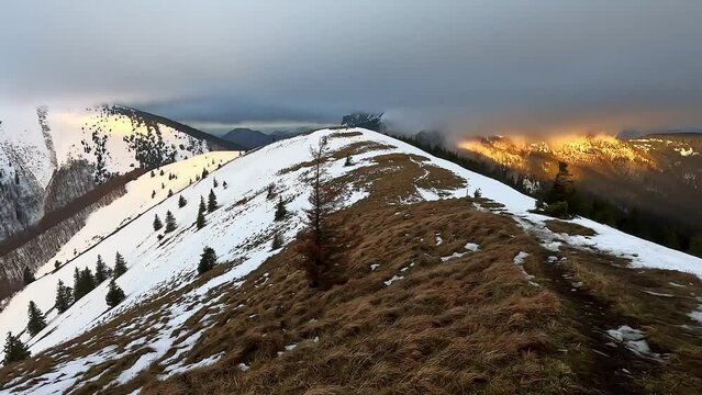 Windy mountain landscape in winter, Hill ridge covered with snow and grass, thick clouds, 