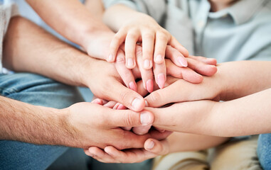 Close-up of several hands placed on top of one another in stack. All family members showing their support to each other. Concept of togetherness, unity, teamwork, family, solidarity, mutual support.