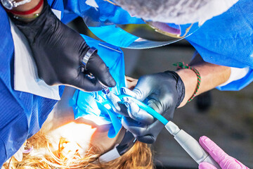 dentist and assistant in gloves treat a diseased tooth