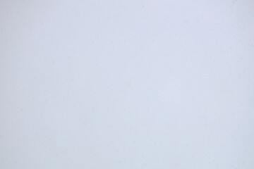 nature background image of light snowfall falling over of snowdrifts. Festive falling snow flakes. Snowstorm dust frozen elements. Snowfall sky white blue. Bokeh snowflakes january. Snow landscape