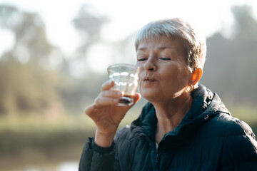 Positive senior, retired women or grandmother with shot grey hair is drinking and enjoying coffee...