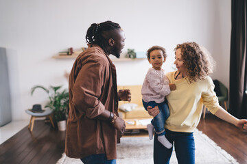 Happy multiethnic family with child standing in living room