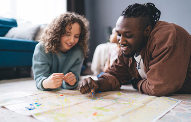 Happy diverse couple with map on floor at home - obrazy, fototapety, plakaty