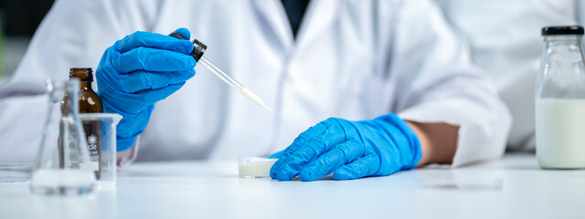 Close up of scientist or nutritionist dripping a sample of milk, fat or glucose in a test tube or...