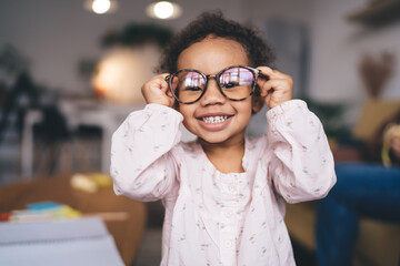 Cheerful ethnic little girl in reflective eyeglasses - obrazy, fototapety, plakaty