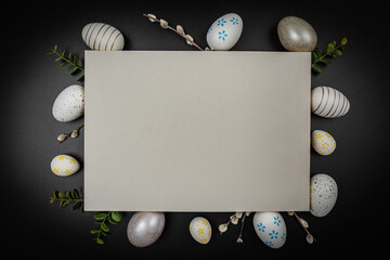 Colorful Easter eggs with willow branches and space for text on empty old paper on black table background, top view