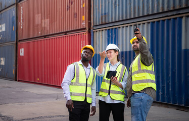 Group of engineers working with laptop in the container yard. This is a freight transportation and distribution warehouse.