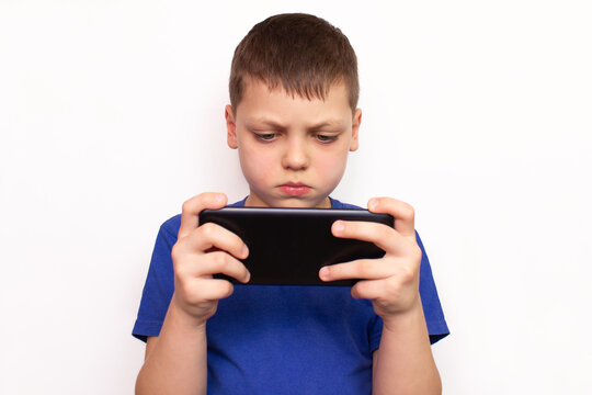 Child with a phone or gaming tablet. Portrait of a Caucasian boy holding a phone in his hands. The problem of modern children, technology addiction on games or watching videos, cartoons, internet