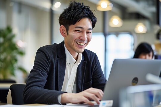 パソコンに向かって笑う日本人男性（打ち合わせ・商談・リモート会議）