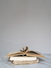 Pile de livres anciens avec un livre ouvert sur le dessus et des pages qui forment un coeur