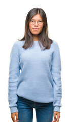 Young asian woman wearing winter sweater over isolated background with serious expression on face. Simple and natural looking at the camera.