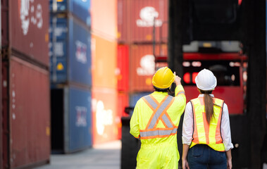 Portrait of Asian woman engineer and worker working with co-worker at overseas shipping container yard.