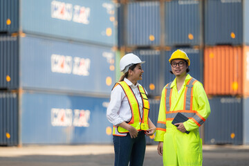 Portrait of Asian woman engineer and worker working with co-worker at overseas shipping container yard.
