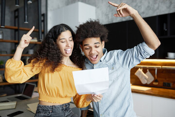 Happy excited african american young couple feeling euphoric while reading paper letter with...