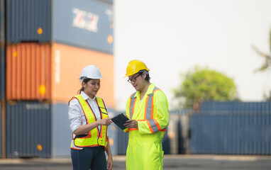 Portrait of Asian woman engineer and worker working with co-worker at overseas shipping container yard.