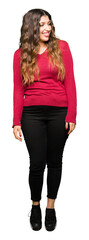 Young beautiful woman wearing red sweater looking away to side with smile on face, natural expression. Laughing confident.
