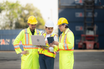 Group of engineers working with laptop in the container yard. This is a freight transportation and distribution warehouse.