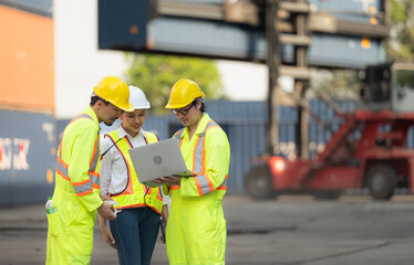 Group of engineers working with laptop in the container yard. This is a freight transportation and distribution warehouse.