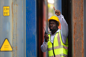 Portrait of male worker holding walkie talkie in front of container