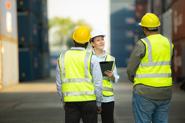 Group of engineers working with laptop in the container yard. This is a freight transportation and distribution warehouse.